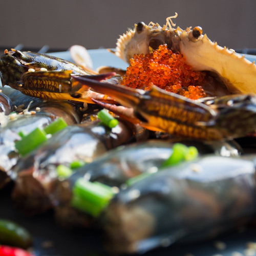 Crab with red roe and green onions on a dark surface
